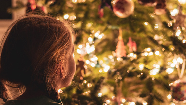 Klein meisje kijkt naar lichtjes in de kerstboom