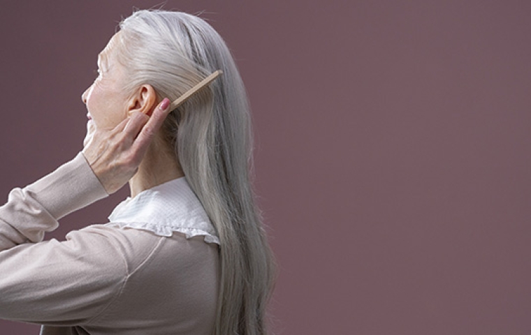 oudere vrouw doet haar grijze haren achter haar oren