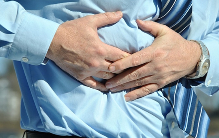 een man in een blauw hemd grijpt naar zijn maag